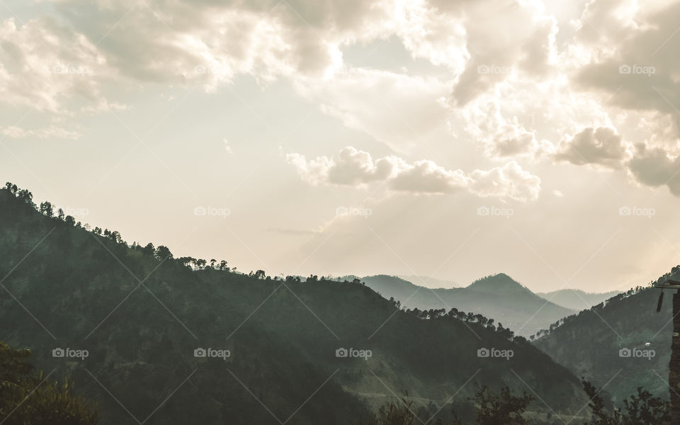 Panorama of winter Annapurna, Nepal Mountain valley in cloud and fog. Sun ray of light coming down from rain cloud during sunset time. Stormy weather, bright sun and copy space.