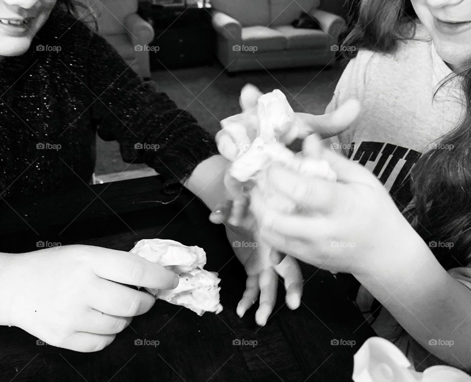 Glimmers Moment Of Happiness High Angle Of Children Sisters  Playing With Textured Pink Slime At The Table And Playing Around With Each Other In Black And White.