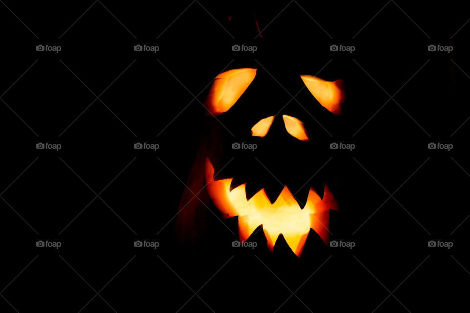 Evil pumpkin face for Halloween in a dark room at night close-up.