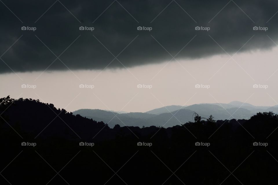 Silhouette of mountain against stormy cloud