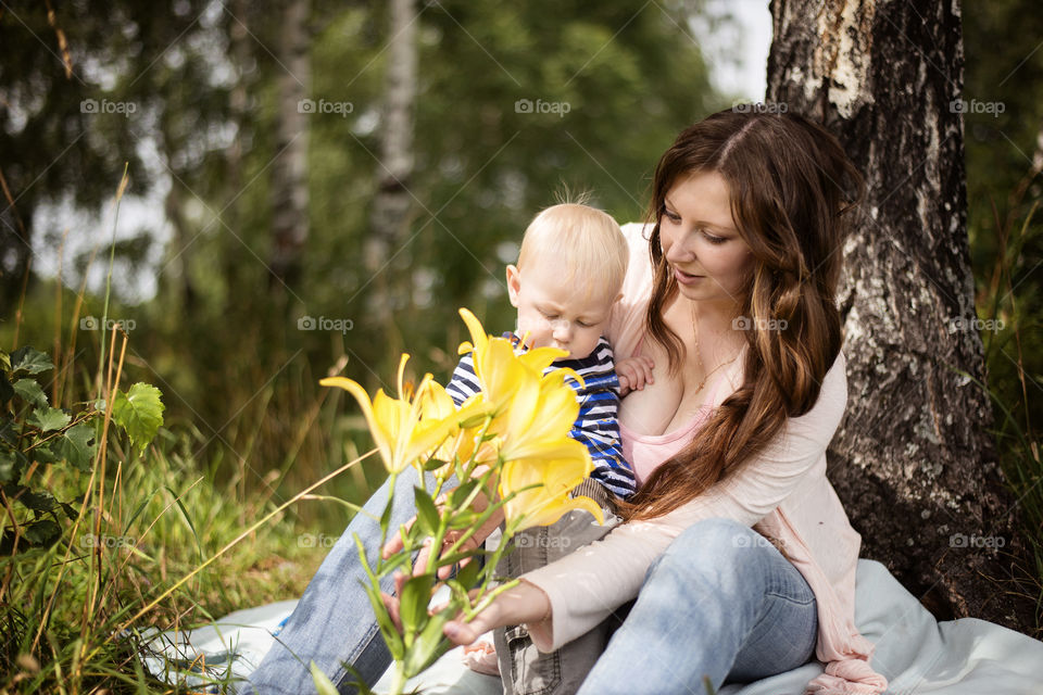 Mother and son sitting in front of flower plant
