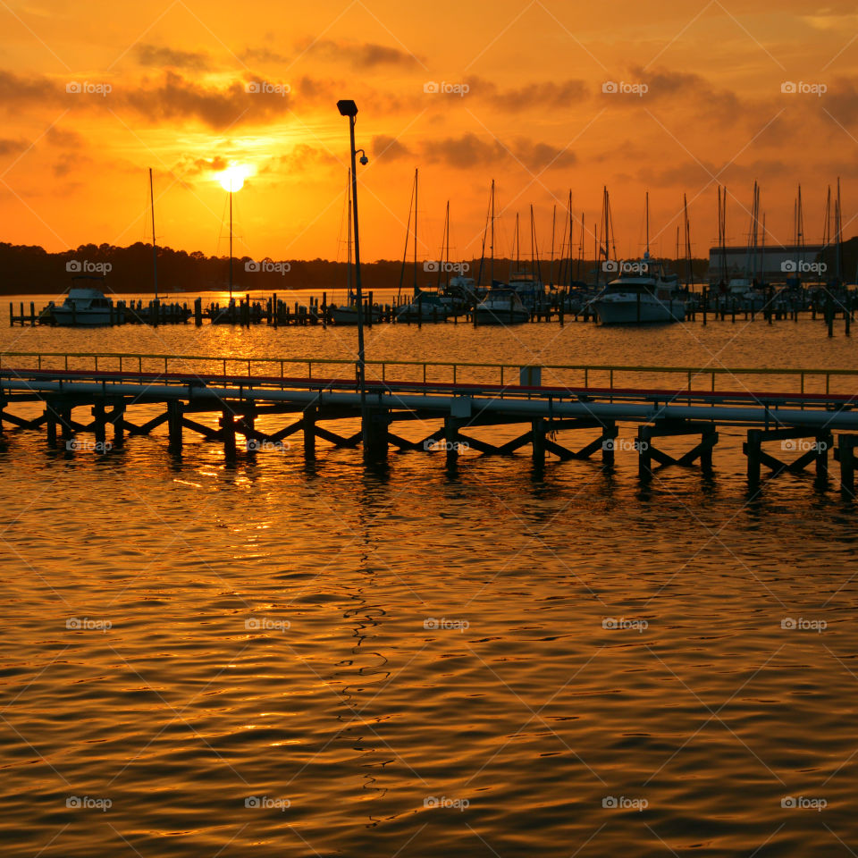 Boats moored at harbor during sunset