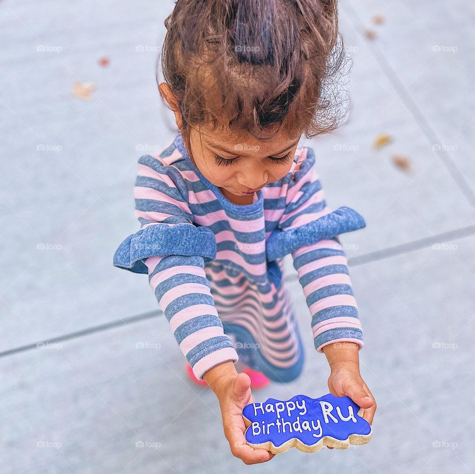 Birthday girl holding sugar cookie, happy birthday cookies, sugar cookies with names, decorative sugar cookies, celebrating toddlers birthday with cookies, birthday party with cookies, cookies made for a special occasion 