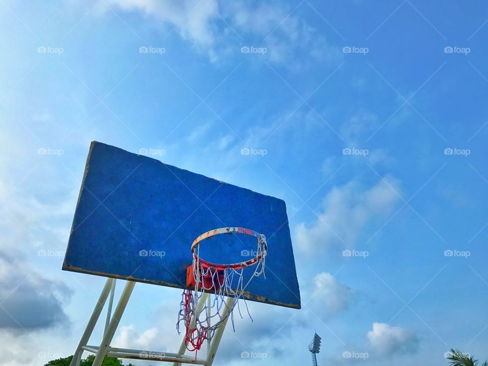 Old basketball board and mesh tear on blue sky background 