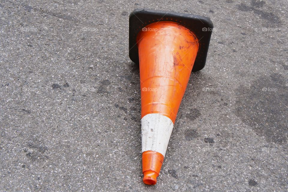 A dirty orange and white traffic cone lying on its side.