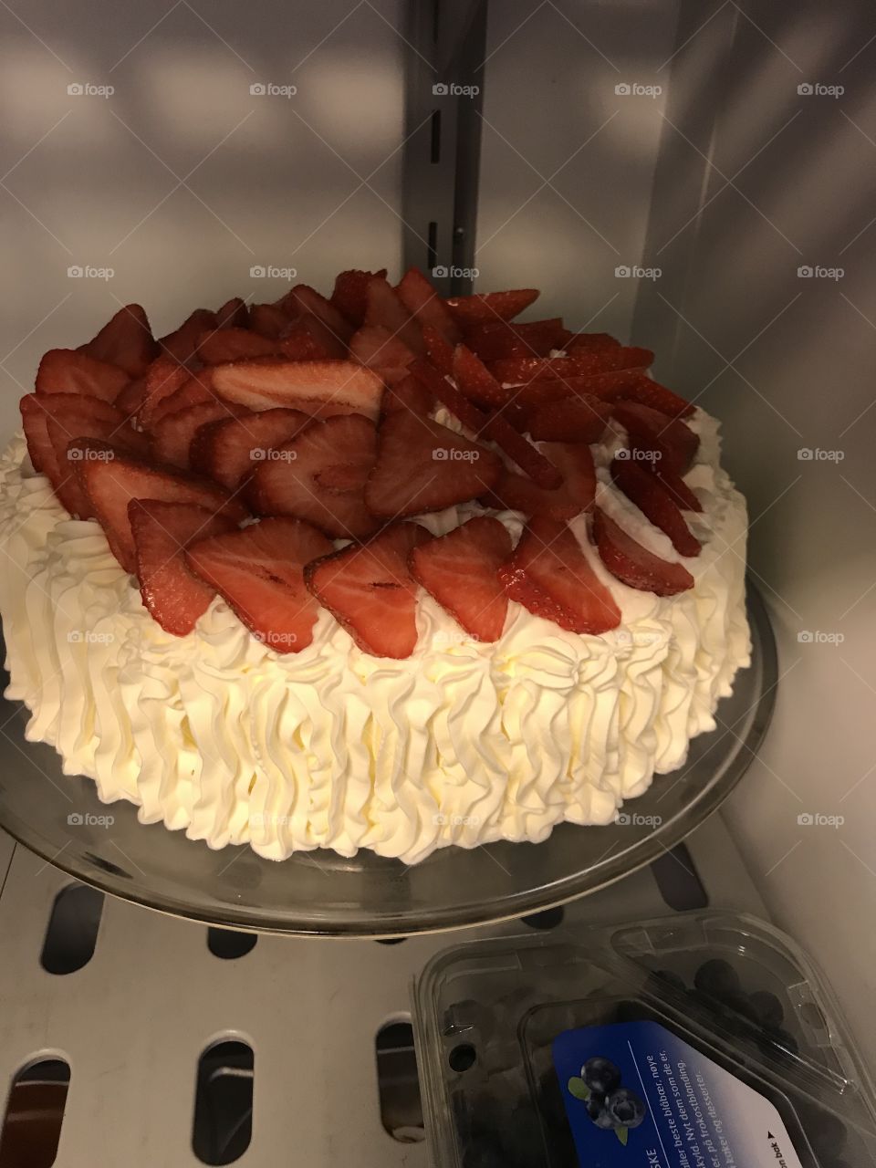 A white cream cake with some really red, nice strawberries on top. It tasted really good, and looked really good too. Dessert preparation for a group.