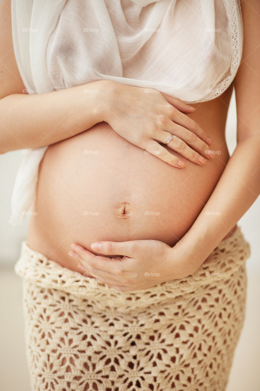 Pregnant belly, a young woman expecting a baby, holds hands on belly