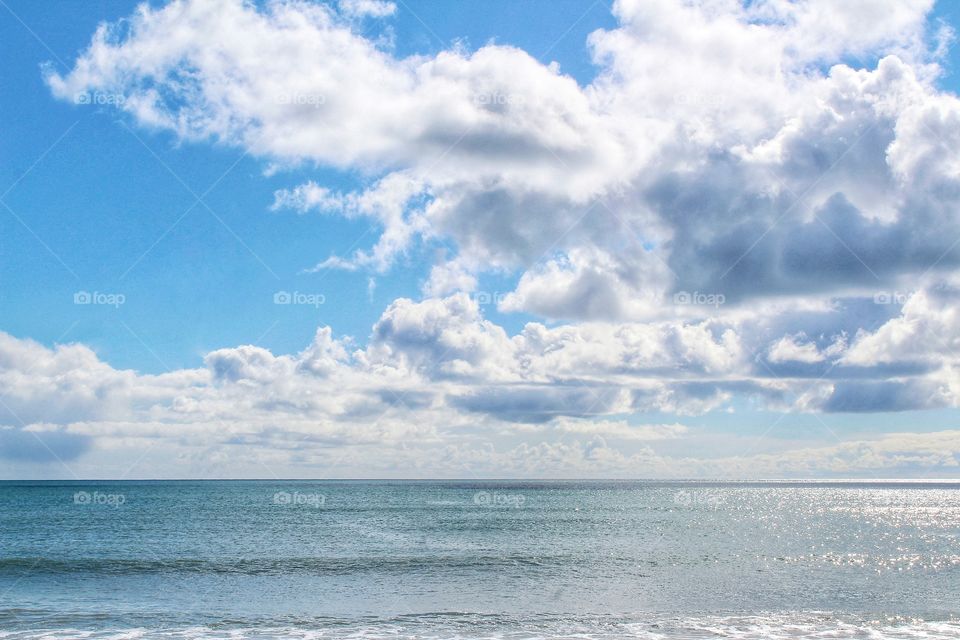 Seascape on a nice sunny day capturing the sea, sky and fluffy white clouds on Marazion beach in Cornwall, England