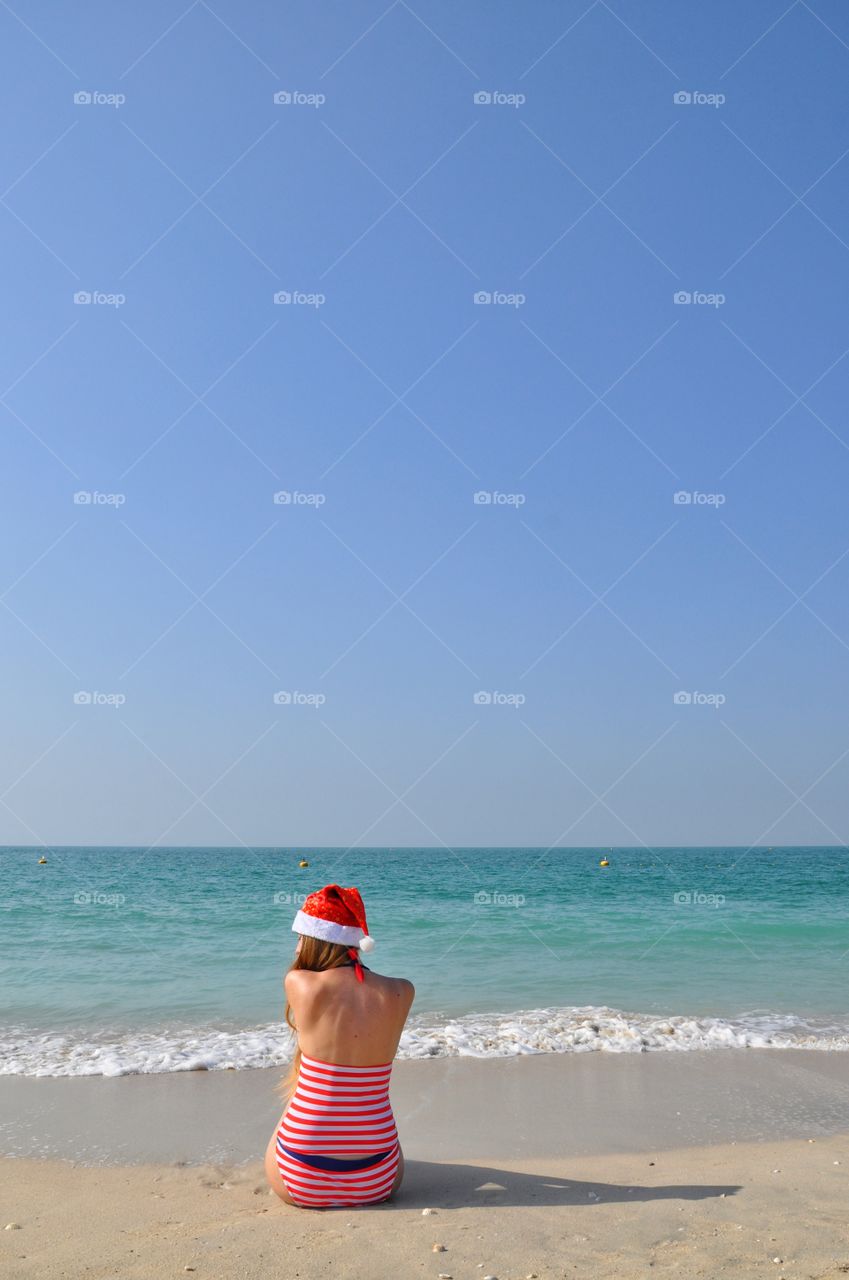 Woman in santa hat sitting on the kite beach in dubai during winter trip