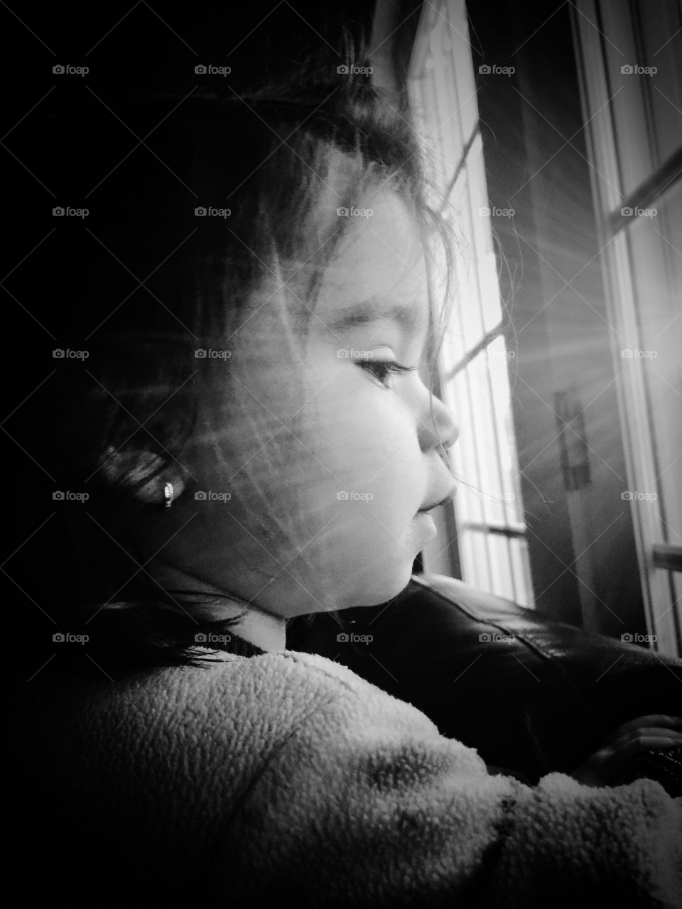 Adorable little girl looking through the window