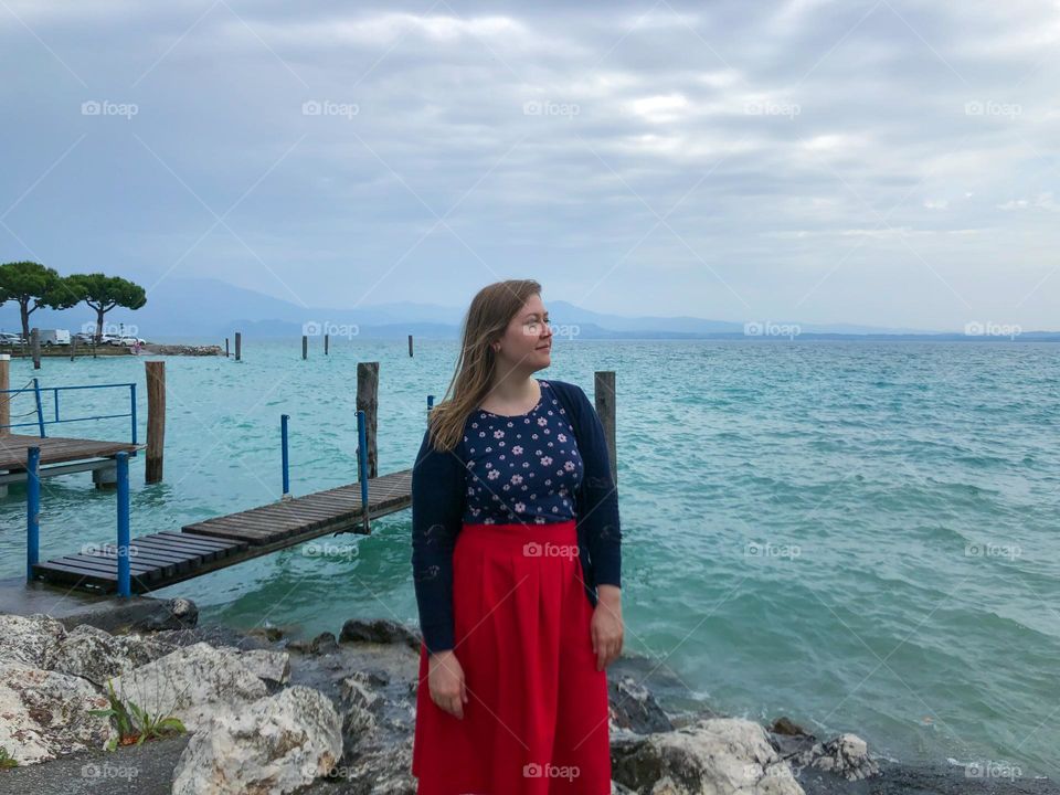 Woman in a navy t-shirt and red skirt near lake Garda in Sirmione Italy 