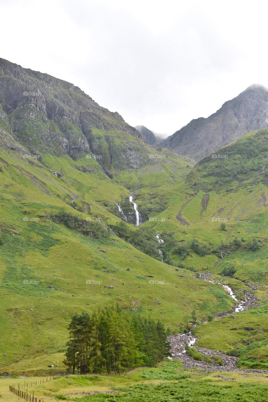 A waterfall flows down the side of a mountain in the Scottish Highlands