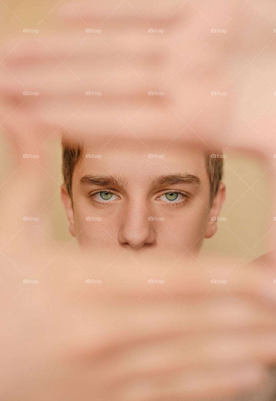Portrait of boy looking through framed hands.