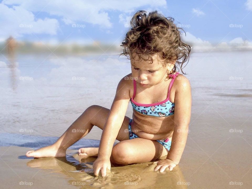 Child playing in the sand at the beach
