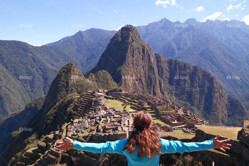 Girl on top of Machu Picchu with open arms owning the mountain