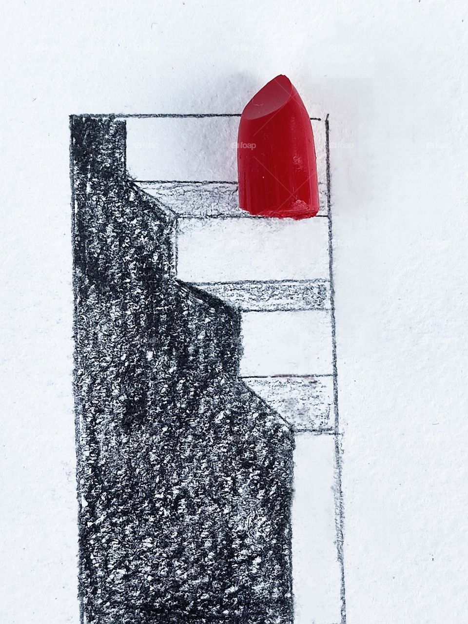 A white sheet of paper on which a 3-d drawing of a staircase is drawn with a black pencil. There is a piece of red lipstick on the stairs. Contrast