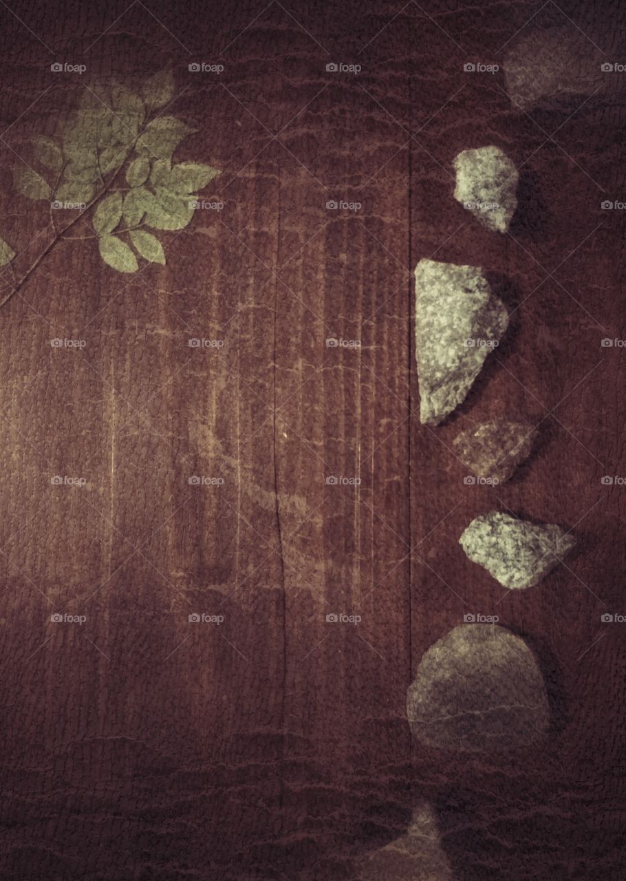 Filtered picture with table art using rocks and a small branch with green leaves
