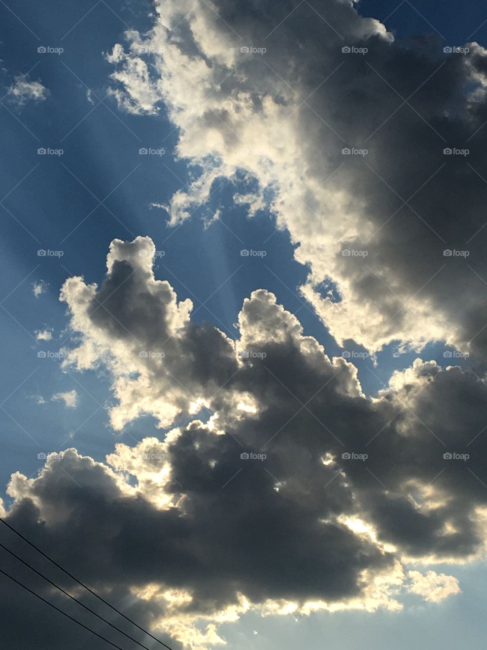 Blue sky with silver-lined dark clouds on hot July day 