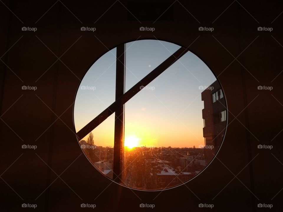 Sunset over Amsterdam through a
 porthole in an hospital elevator