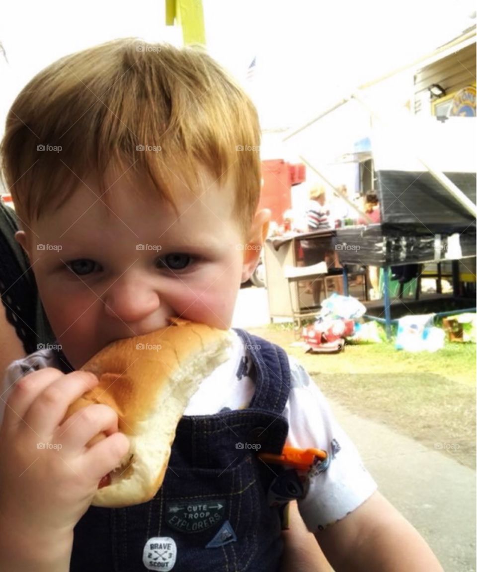 Red Headed Toddler Eating Hot Dog at the Fair