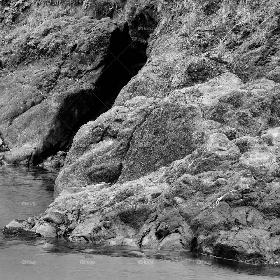 The tide begins to move in along the side of a cliff on the Oregon coast. 