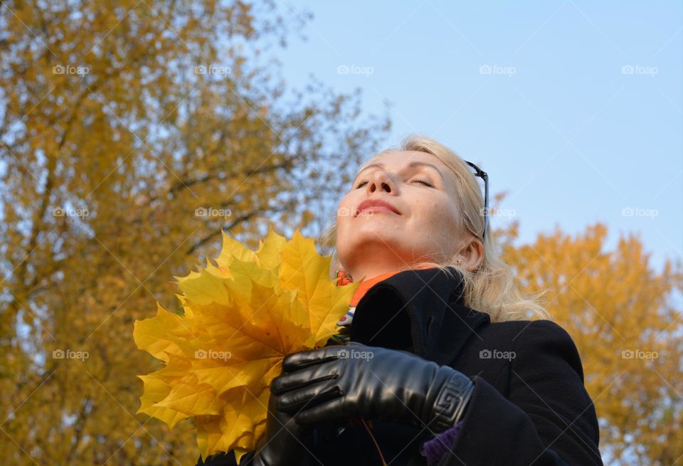 demi season woman with yellow leaves relaxing outdoor