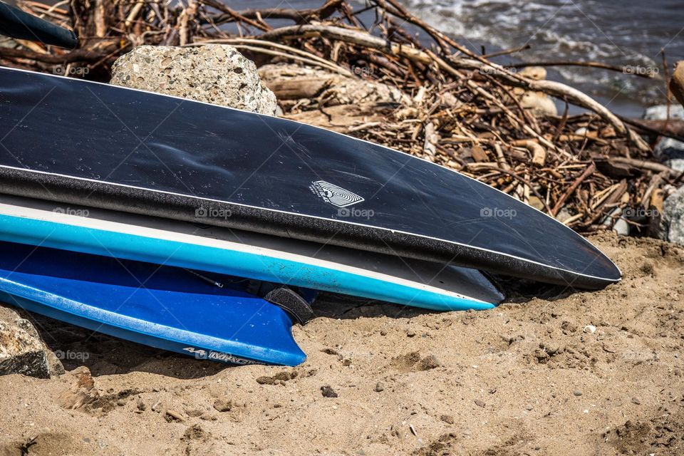 Two surfboards and a boogie board resting on the beach on a warm summer afternoon 