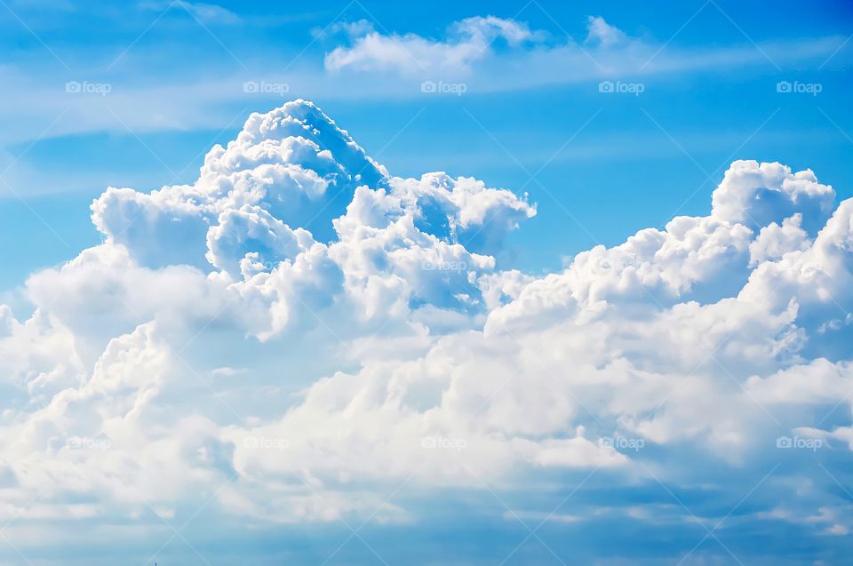 Some clouds in the sky with an unforgiving blue sky in the background