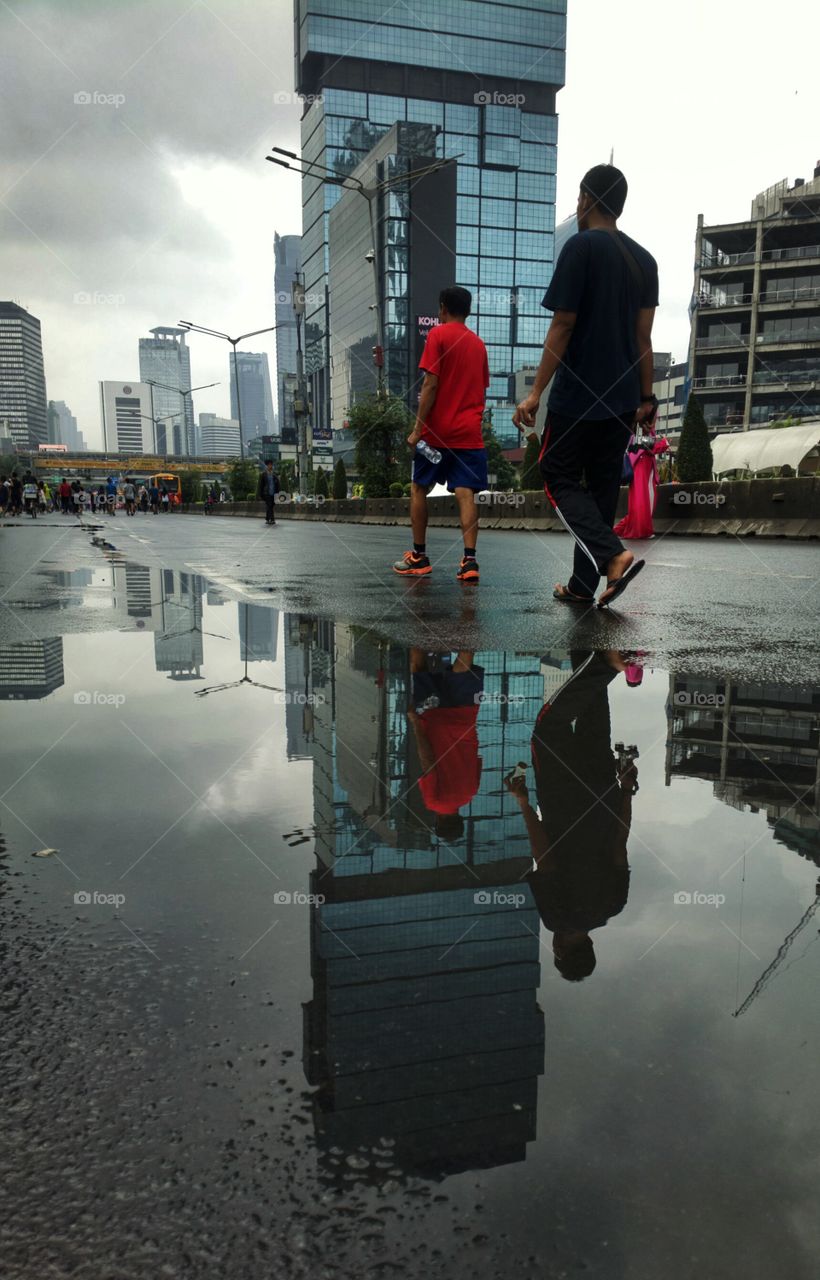 reflections of men walking and UOB Plaza