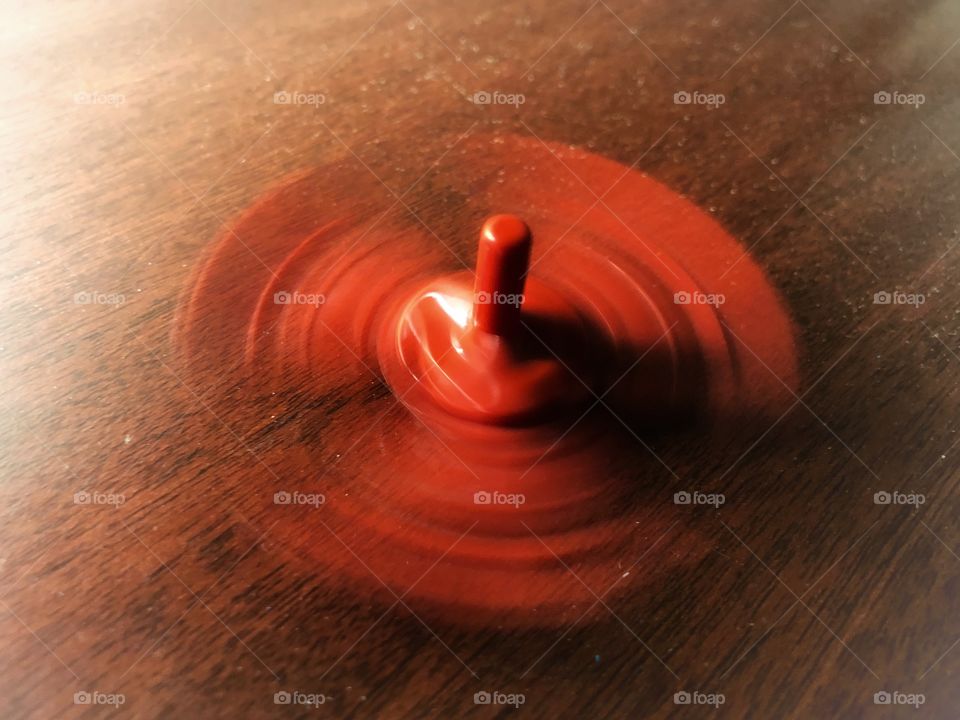 Red Spinning Top Toy, spinning, creating a beautiful blur effect. A toy, a stress reliever, a relaxing tool. A very useful and simple toy to keep around.
