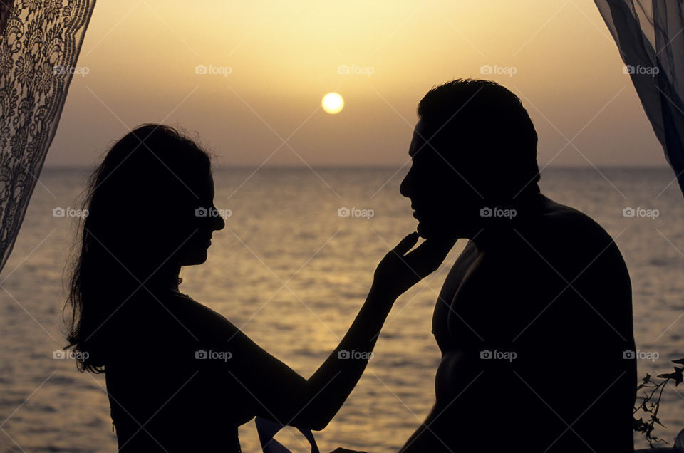 Silhouette of couple embracing at Sunset by the ocean. 