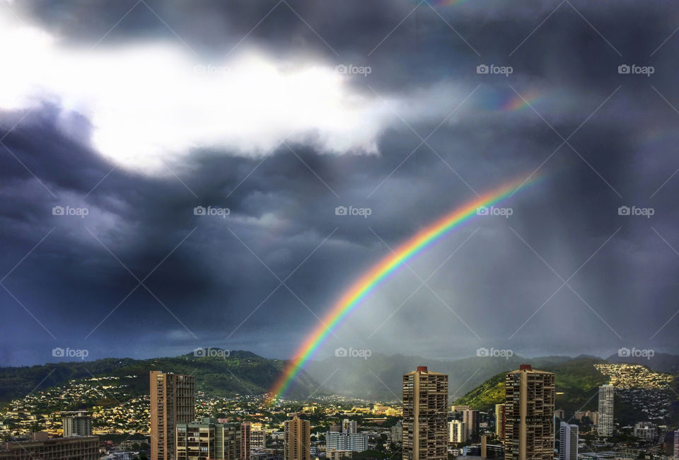 Rainbow in a stormy sky over Honolulu city landscape 