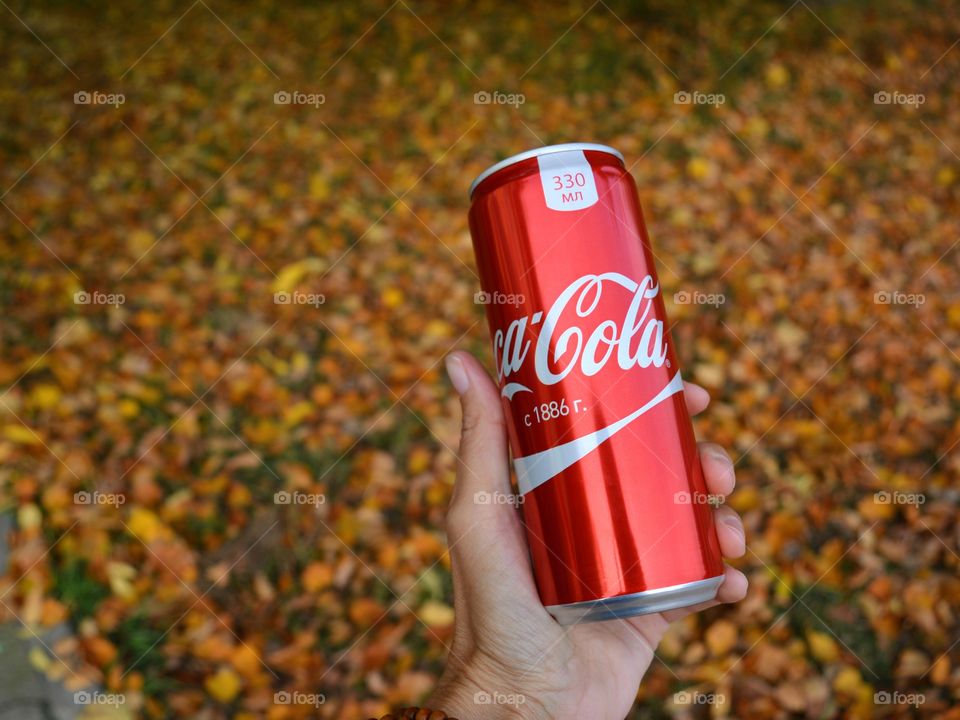 coca cola in hand autumn background, drinking coca cola outdoor