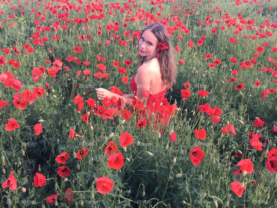 Woman in  red dress in a field of poppies