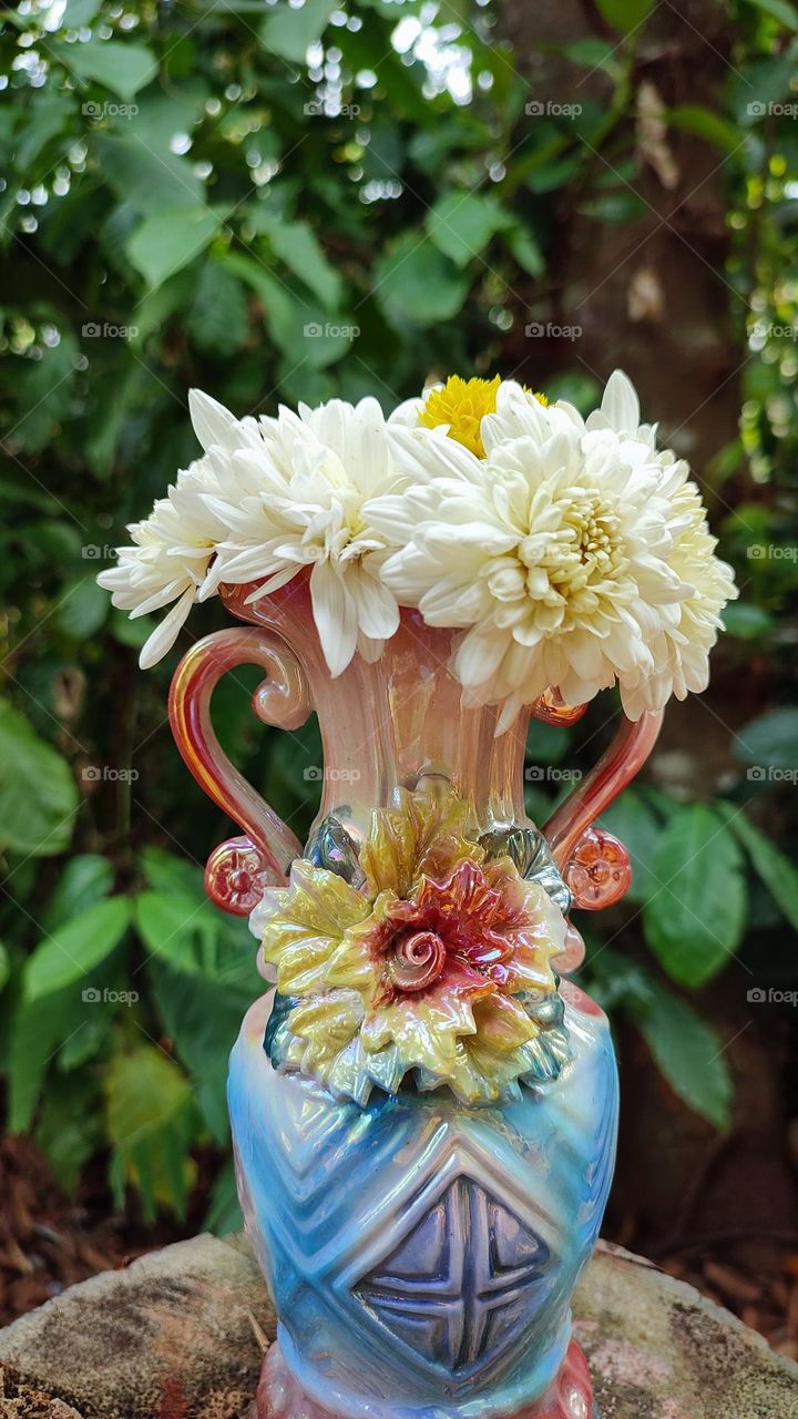 Beautiful white flowers in a colourful flowerpot with a flower sculpture, Flowers in a vase, colourful vase, white flowers in a vase