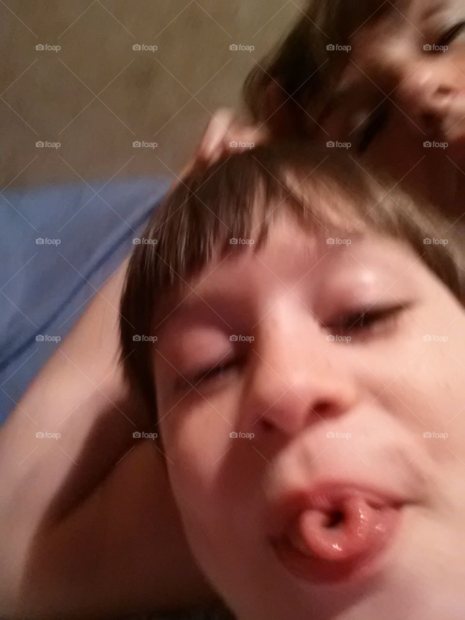 Six year old boy doing a silly face and curling his tongue.