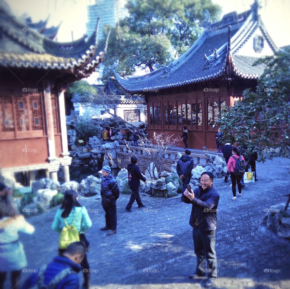 Enthusiastic tourist takes a picture with the smartphone at the Yu Garden in Shanghai