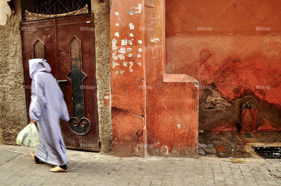 Moroccan woman lady slightly blurred walking down the street in Marrakech after having done grocery, people of Marrakech