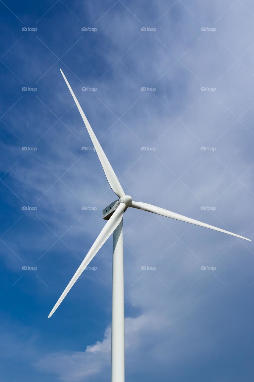 White coloured wind turbine operating in the northern part of Sri Lanka with sky and white clouds in the background.