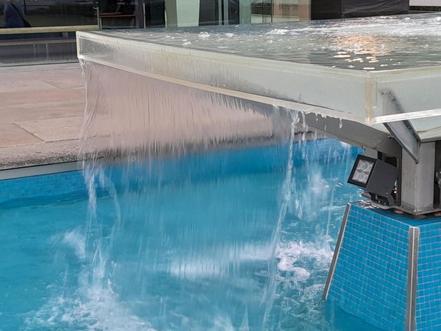 a wall of water, pouring out and over, forming a small waterfall