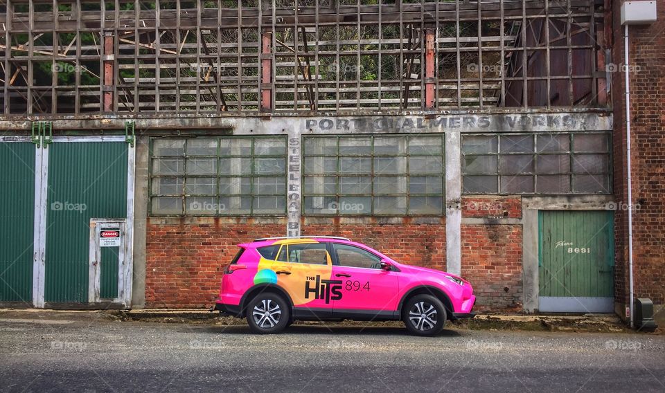 New car with advertising parked in front of old warehouse building