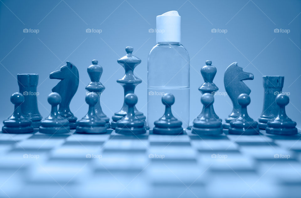 Coronavirus concept image chess pieces and hand sanitizer on chessboard illustrating global struggle against novel covid-19 outbreak.