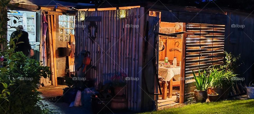 Behind this wall is a small shed that is colloquially entitled “Ron’s Whiskey Lounge”. People sit together here to enjoy alcoholic beverages not limited to whiskey. The title simply says: “Drinkers are welcome !!!” 2023. Hypnotic Productions