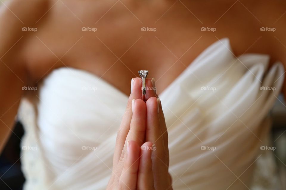 Bride holding engagement ring between hands