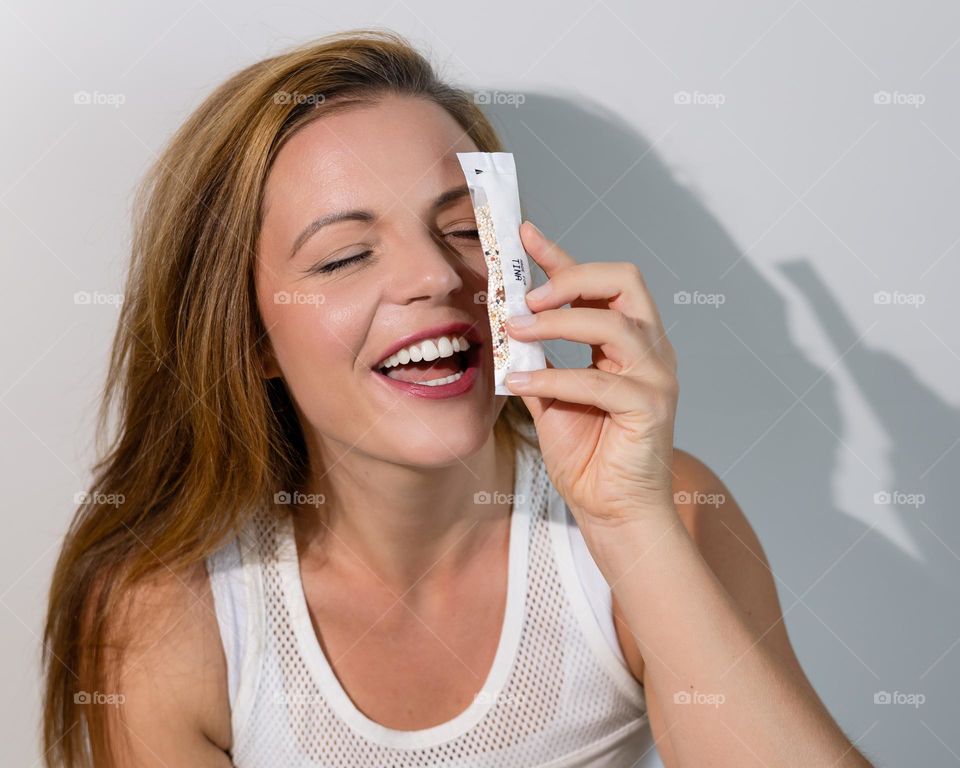 Portrait of a laughing young woman with a product