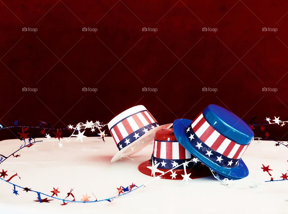 Tiny party hats in red, white, and blue with the Stars and Stripes for hat bands on a table with confetti. 