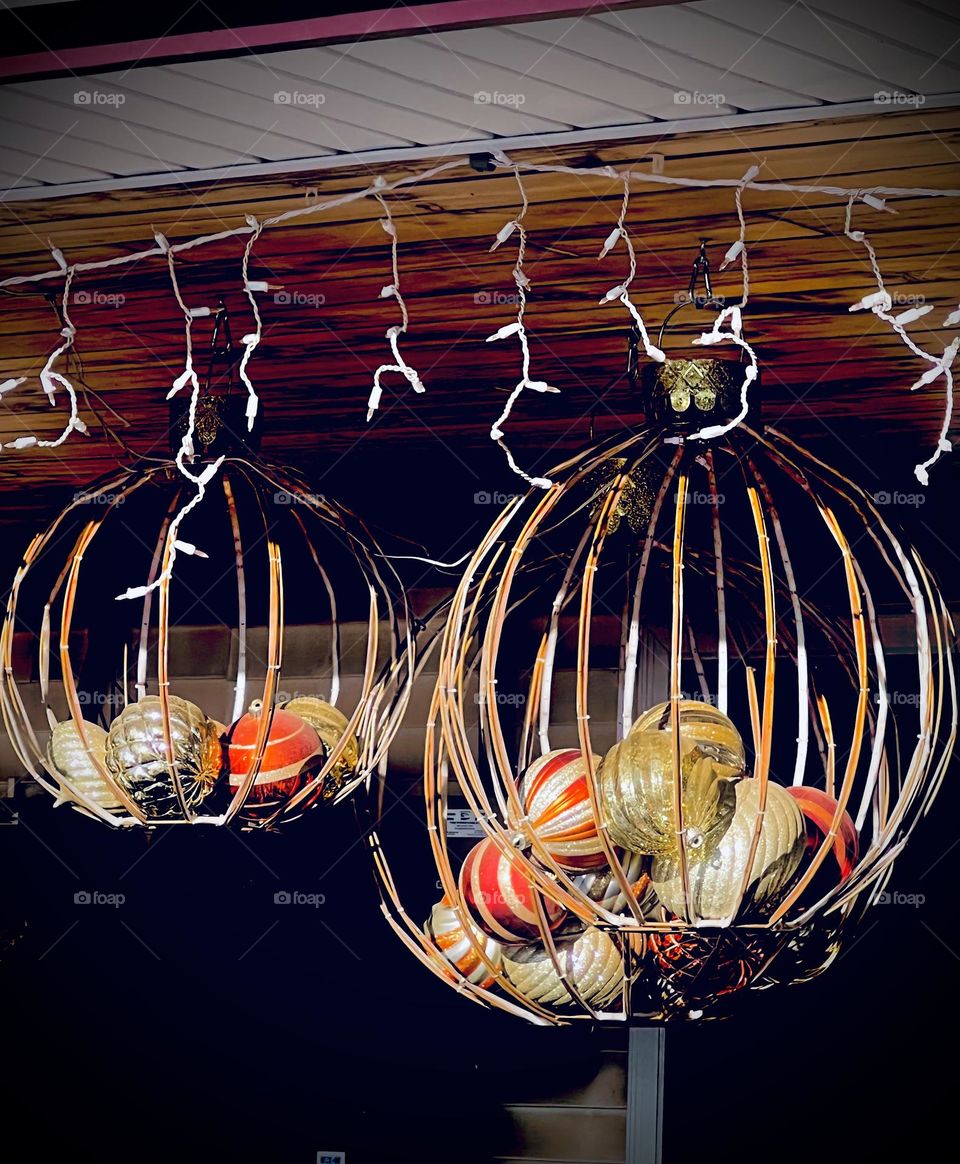 An outdoor winter decoration with ornaments and Christmas lights during the day.