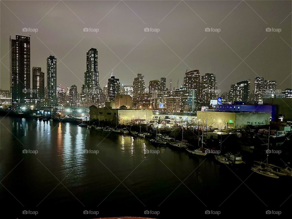 This is “Newtown Creek” seen from the “Pulaski Bridge” that connects “Greenpoint”, Brooklyn to LIC, Queens on an evening in early December 2023. Across the water we see LIC and behind it “Manhattan”. Hypnotic Productions