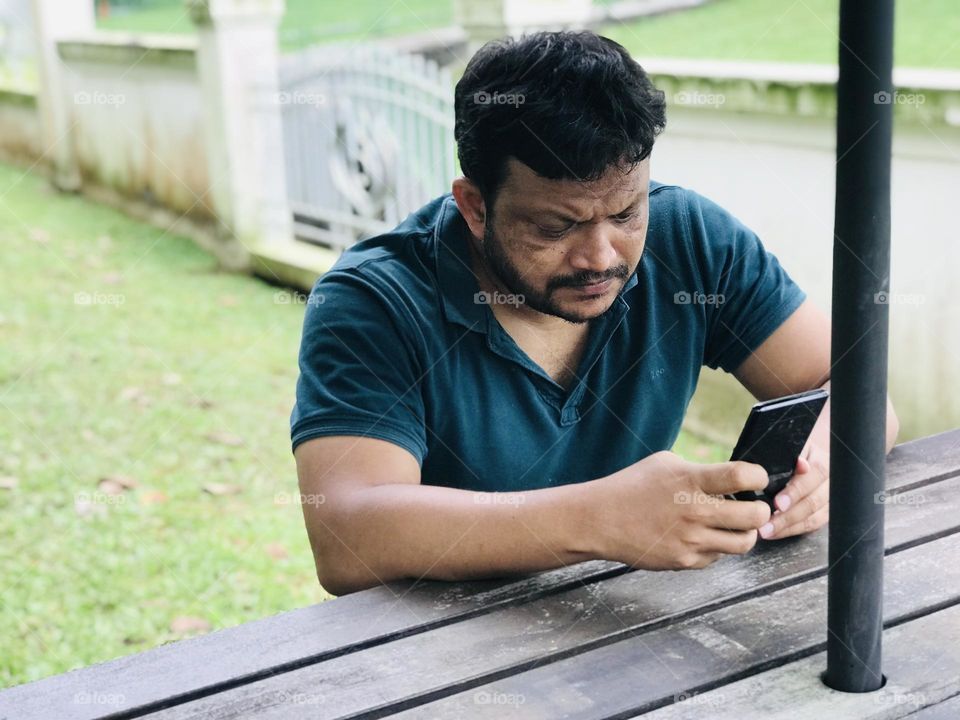 Person with phone and watching some thing in the phone at outdoor table 