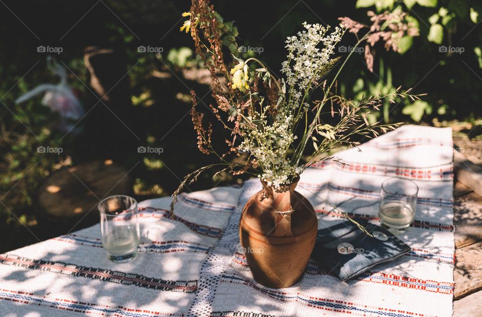 Wild flowers in a vase, while having a picnic in the countryside at the beginning of spring.